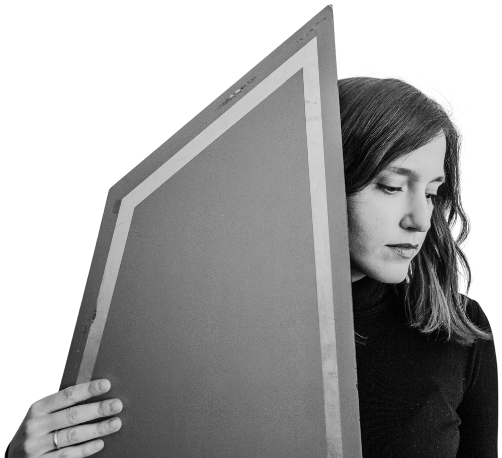 Gosia Klajn holding a large framed panel beside her face